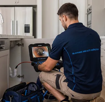 Plumber clearing a blocked toilet in a Killara bathroom